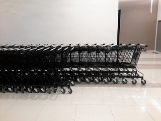 empty supermarket carts or trolley black color in a row at hypermarket and ready for shopping.