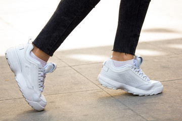 A girl wearing white sport sneakers on outdoor