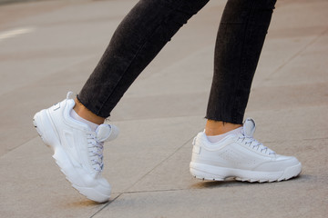 A girl wearing white sport sneakers on outdoor