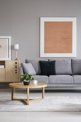 Real photo of a painting on a grey wall in an elegant living room interior with a sofa and round table