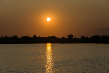 Orange sunset over trees and a lake