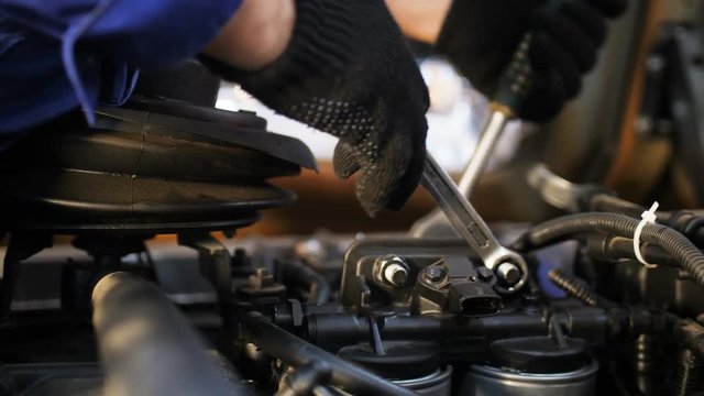 technician twists screws on truck engine at checking closeup
