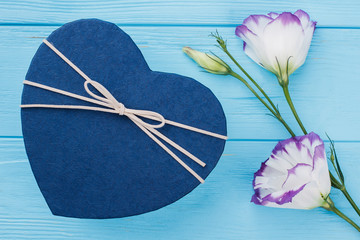 Blue heart shaped box and flowers. Beautiful lisianthus eustoma flowers. Blue wooden table background.