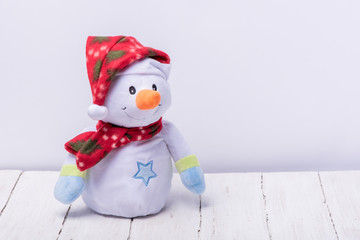 Funny snowman in a red hat and scarf on a white background