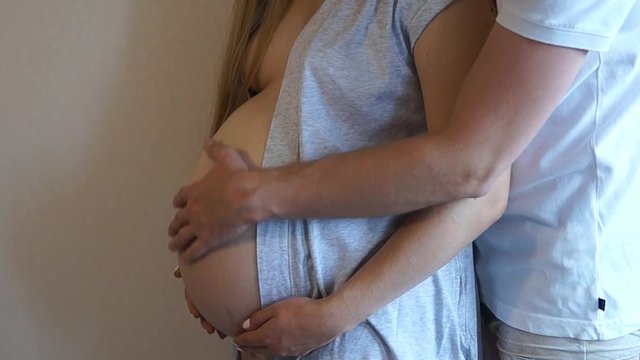 Mom and dad hands on pregnant tummy. Pregnant couple caressing pregnant belly.