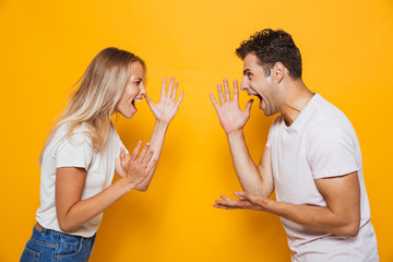 Young loving couple standing isolated over yellow wall background quarrel.