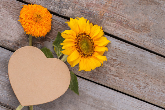 Love concept, sunflowers. Blank heart shape cardboard. Old vintage wooden desk surface background.
