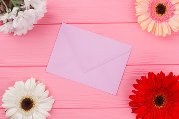 Purple envelope and beautiful flowers on wood. Pink wooden table background.