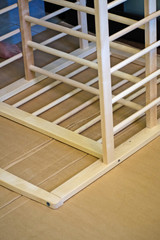 Joiner collects a new baby cot with a hand tool. The man is picking up a children's wooden crib. Waiting for the baby.