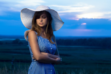Naklejka premium dramatic portrait of a beautiful girl in a hat in the field, a young woman is walking in the summer outdoors