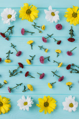 Yellow chamomile and dahlila flowers. Flat lay, top view. Blue wood background.