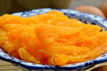 Golden egg strip is Thai desserts made from eggs with Thai style bowl on wooden background ( Thai name is Foi Thong).