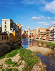 Fototapeta na wymiar Scenic landscape of picturesque multocolor houses overlooking the river Onyar with red metal brige in Girona Spain 