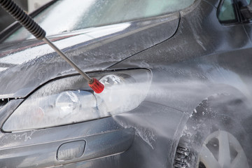 Mann sprüht Autoshampoo bei Autowäsche in Auto SB Waschbox mit Hochdruckstrahler auf