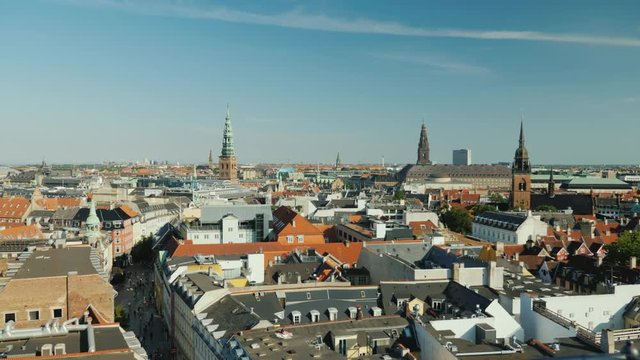 The city of Copenhagen, an old city often with old-tiled roofs and spiers. Pan shot