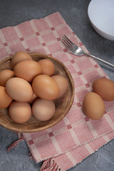 Fresh chicken eggs in the basket for cooking or dessert on grey background