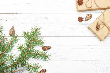Gifts for new year wrapped in craft paper near spruce branches and cones on white wooden background...