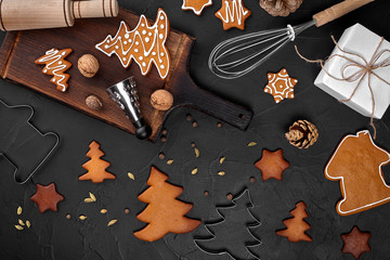 Obraz na płótnie Canvas Christmas homemade gingerbread cookies, spices and cutting board on dark background with copy space for text top view. New year and christmas postcard
