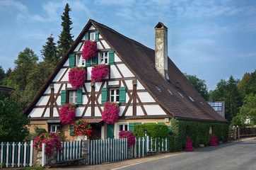 Schönes altes Fachwerkhaus mit roten Blumen an den Fenstern