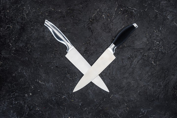 top view of two kitchen knives arranged on black surface
