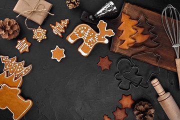 Christmas homemade gingerbread cookies, spices and cutting board on dark background with copy space for text top view. New year and christmas postcard
