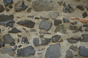 Alte Steinmauer mit verschiedenen grauen und schwarzen Steinen 