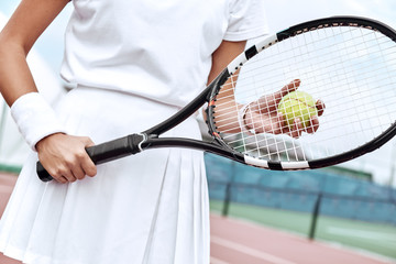 Close up of a young woman ready to hit a tennis ball, serving a ball during game.