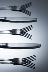 close-up view of shiny forks and knives reflected on grey