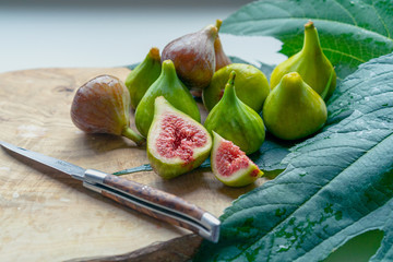 Fruits of fig tree with leaves on white background/ Fresh figs with leaves on rustic wooden table/...