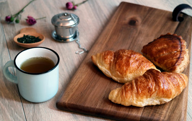French croissants with tea and tea infuser in background, concept for breakfast 