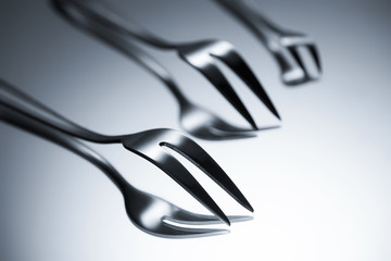 close-up view of forks with two tines reflected on grey