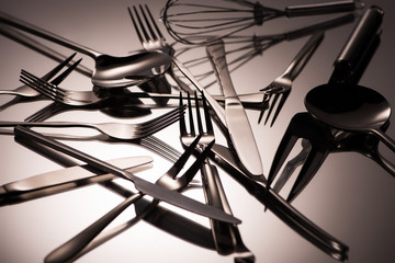 close-up view of various shiny stainless steel utensils on grey