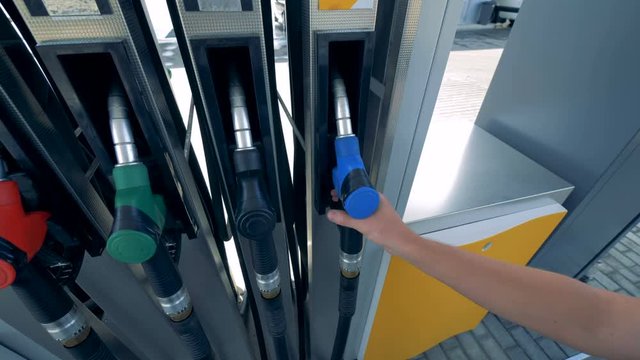 Male hand is putting out a gas nozzle from its pump. Gasoline, gas, fuel, petroleum concept.