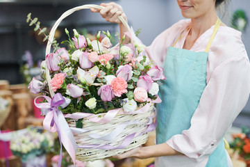 Mid section portrait of unrecognizable female florist holding flower basket with beautiful pastel colored roses while working in flower shop - Powered by Adobe