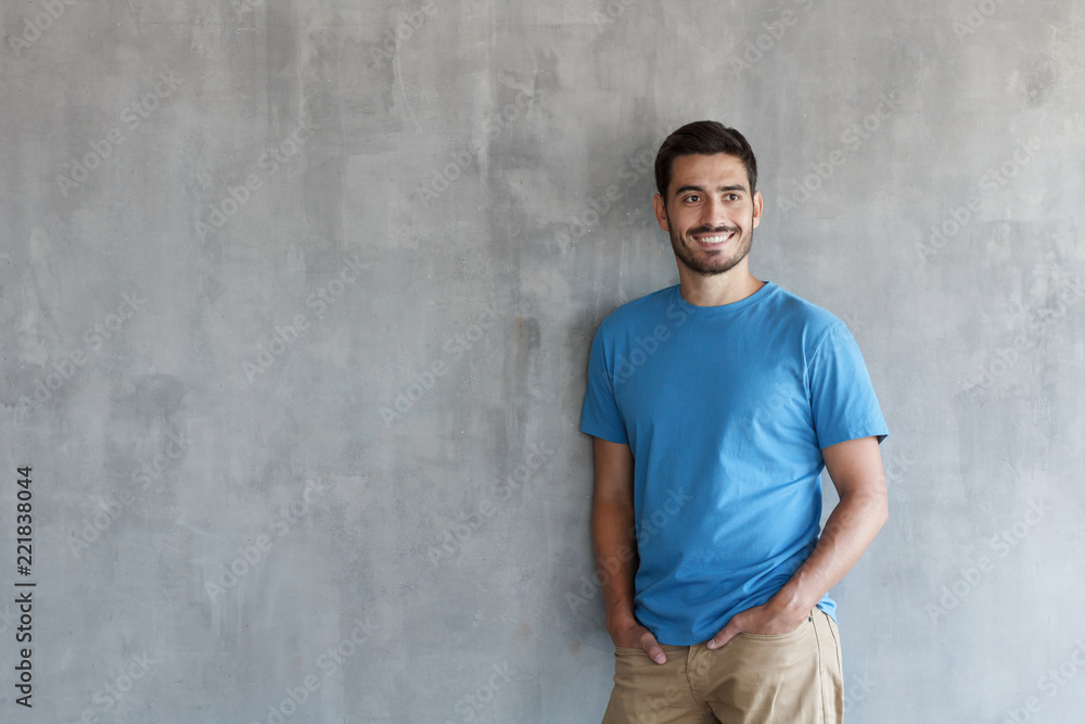 Wall mural indoor photo of handsome european guy pictured isolated against grey textured wall standing in blue 