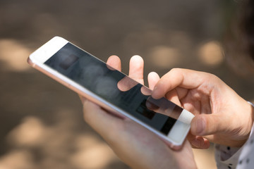 Close up of business person's hand holding and touching cell phone screen.