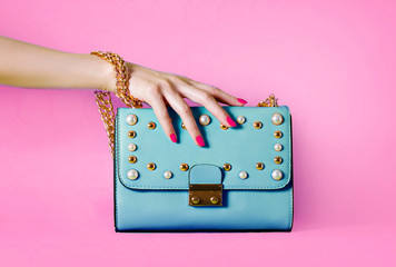 Sky blue handbag purse and beautiful woman hand with red manicure isolated on pink background. - 221838665