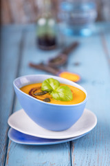 Pumpkin cream soup with pumpkin seeds, pumpkin oil and turmeric on a blue background