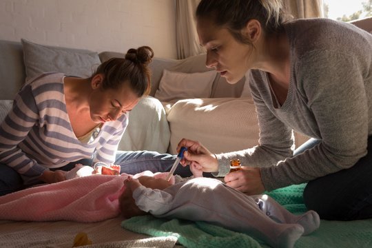 Lesbian couple feeding medicine to their babies