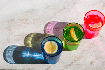 top view bright glass with drink and lemon slice, beautiful shadow on a stone marble table  ,detox, creativity,fashion concept