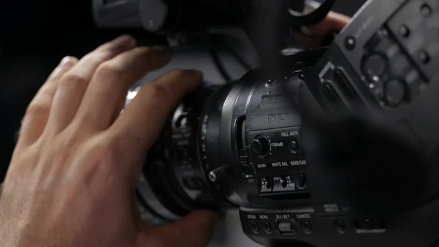 The cameraman is working behind the camera.