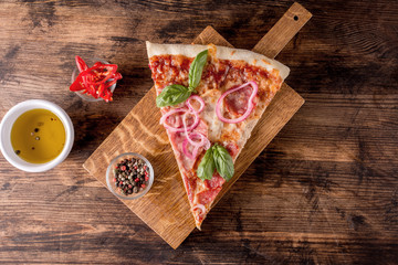 Piece of pizza on a wooden background in rustic style.