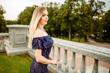 Fashionable portrait of style. Young beautiful woman in a blue long dress posing on the stairs against the old city building.The girl is outdoors