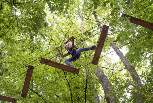 Girl doing adventure park tree climbing parcours