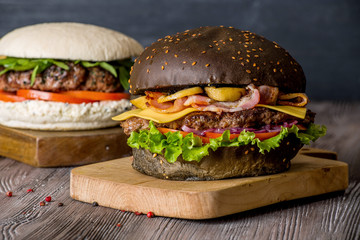 Hamburger with beef and bacon and a white hamburger with french fries on a wooden background.