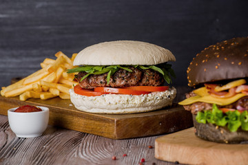 Hamburger with beef and bacon and a white hamburger with french fries on a wooden background.