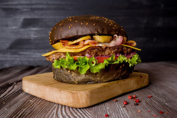 Delicious hamburger with beef and bacon on a wooden background.