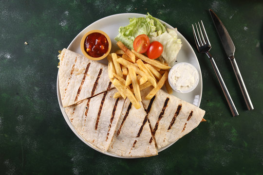 	quesadilla  with fried potato and salad on a wooden background