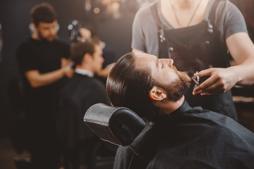 Hipster client man visiting in barber shop shaving beard scissors