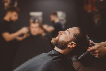 Barber shop. Man in barbershop chair, hairdresser styling his hair